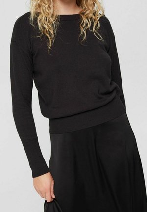 Sort langærmet sweater med løs pasform, ribbet kant og blød tekstur, parret med en matchende sort nederdel. Enkelt, minimalistisk design.