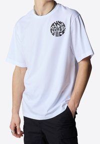Biała bawełniana koszulka z krótkim rękawem i okrągłym dekoltem. Zawiera czarne okrągłe logo "The North Face" po lewej stronie klatki piersiowej. Luźny krój.