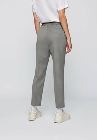 Pantalons rayés gris clair avec une taille élastique, coupe slim et longueur cheville. Comprend deux poches latérales et une texture de tissu lisse.