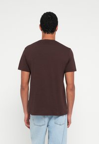 Tricou maro cu mâneci scurte și guler rotund, din bumbac, cu un design simplu și croială lejeră, vedere din spate.