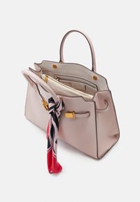 Sac à main en cuir beige avec fermoir doré, double poignée, intérieur ouvert montrant une pochette zippée, et un foulard avec un motif rouge, noir et blanc attaché à une des poignées.