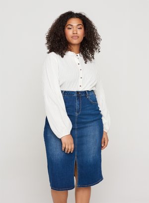 Weißes Hemd mit vertikalen Rillen und langen Ärmeln, kombiniert mit einem hoch taillierten blauen Jeans-Midi-Rock mit einem Schlitz vorne.