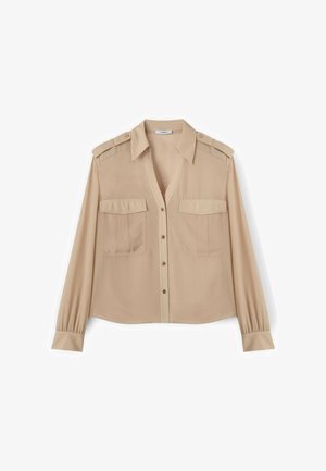 Camisa beige de manga larga con botones, dos bolsillos con solapa en el pecho y hombreras, con cuello clásico y mangas con puños.