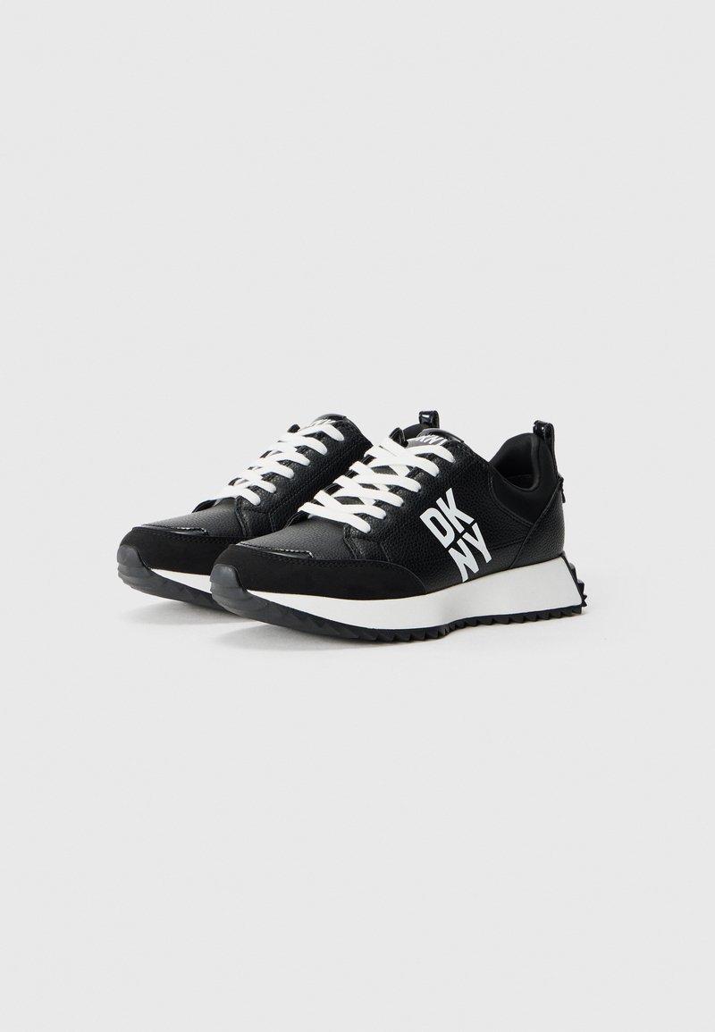 Baskets noires avec un matériau texturé, lacets blancs et une semelle blanche contrastante. Présente un grand logo « DKNY » en blanc sur le côté.