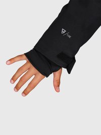 Hand, die aus dem Ärmel einer schwarzen wasserdichten Jacke mit verstellbarem Velcro-Bündchen und innerem Daumenloch hervortritt, beschriftet mit "10K".