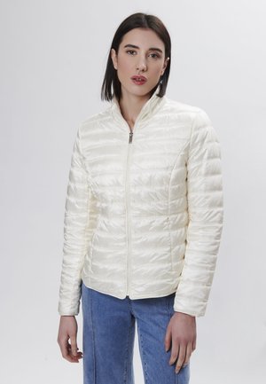 Giacca trapuntata avorio con chiusura a zip, colletto alto e maniche lunghe. Realizzata in tessuto leggero e lucido. Design semplice senza motivi visibili.