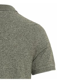 Donkergroen getextureerde polo shirt dat de kraag en schouder toont. Korte mouwen en een subtiel patroon zijn zichtbaar. Zachte stofafwerking.