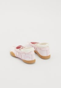 Sapatos de lona cor-de-rosa com solas de borracha, apresentando um padrão floral texturizado nas laterais e atacadores brancos, desenhados com um silhueta de perfil baixo.