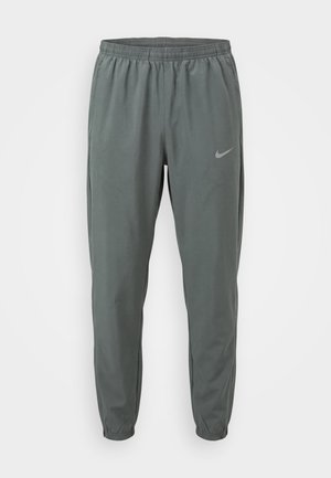 Γκρι αθλητικό παντελόνι Nike με ελαστική μέση και μανσέτες, με μικρό ανακλαστικό λογότυπο Swoosh στο πάνω αριστερό μηρό.