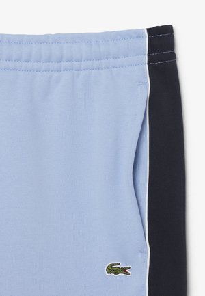 Pantaloncini con fascia elastica azzurro chiaro, pannelli laterali blu navy, piping bianco, tasca laterale e piccolo logo verde di coccodrillo vicino all'orlo.