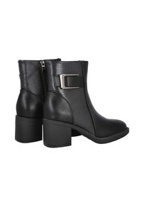 Un par de botas negras hasta el tobillo con tacones de bloque, paneles laterales texturizados, un cierre de cremallera lateral y una gran hebilla metálica rectangular en el lado exterior.