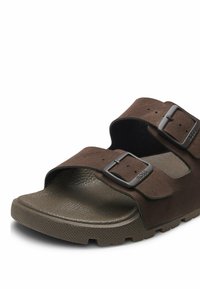 Brauner Wildleder-Slidesandale mit zwei verstellbaren Schnallenriemen und strukturiertem Absatz, Nahaufnahme von vorne und seitlich.