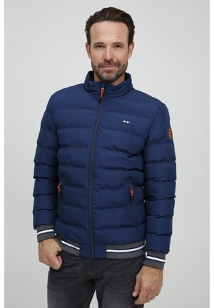 Marineblauwe pufferjas met gequiltde textuur, staande kraag, oranje ritssluiting accenten, twee zijzakken en contrasterende gestreepte boorden en zoom.