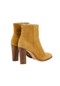 Bottes cheville en daim fauve avec talons épais superposés et fermetures éclair latérales, vues de l'arrière et de côté sur un fond blanc.