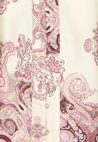 Tissu crème avec un motif floral cachemire rose et marron, présentant des boutons recouverts de tissu le long du centre vertical.