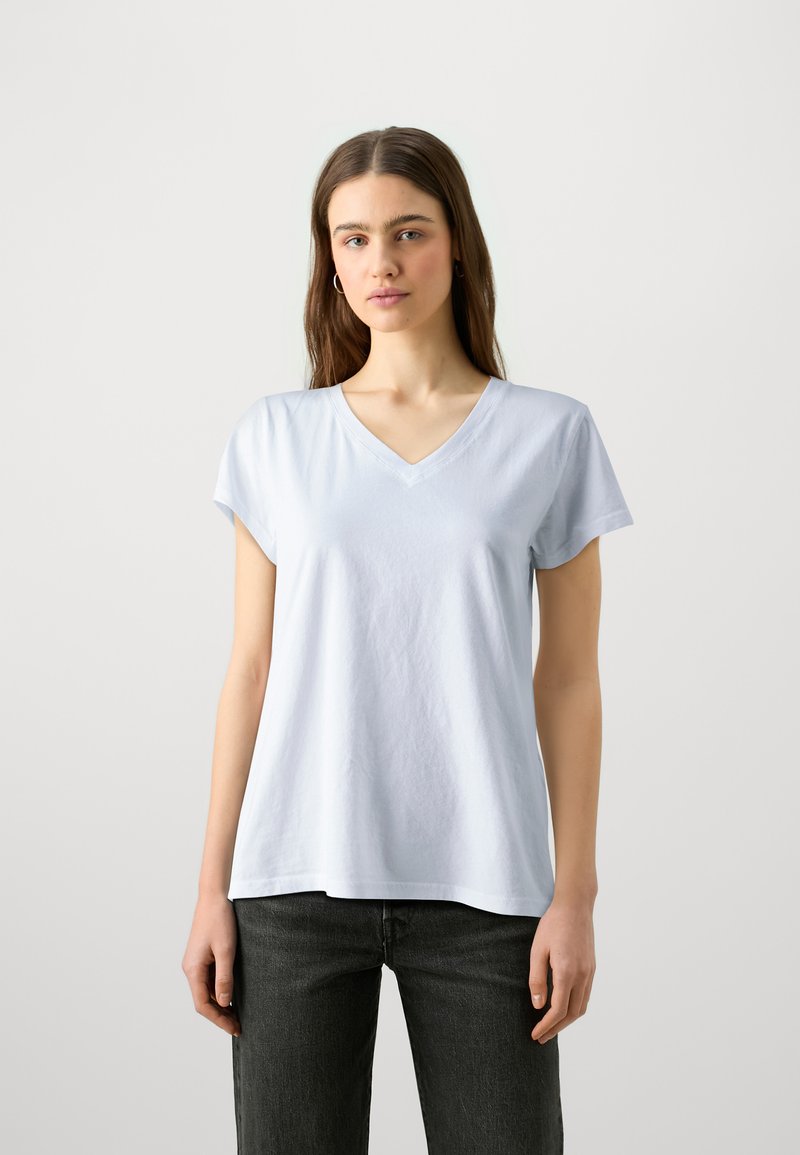 Lyseblå V-hals t-shirt lavet af blød bomuld, med korte ærmer og løs pasform, parret med mørke denim jeans.