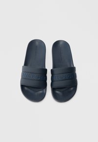 Μπλε-σκούρες σαγιονάρες με υφή στον ιμάντα που περιλαμβάνει οπές. Λογότυπο "HILFIGER" ανάγλυφο στον ιμάντα. Επίπεδες σόλες με λεία επιφάνεια.