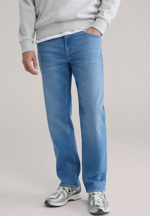 Lichtblauwe spijkerbroek met een rechte pijp, voorzien van een klassiek ontwerp met vijf zakken en subtiele vervaging. Gecombineerd met grijze sneakers.