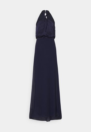 Laivansinis ilgas vakarinis suknelė su halterio kaklo ir susiraukšlėtu liemeniu. Sijonas krenta iki grindų, pasižymintis lygiu paviršiumi ir minimalistiniu dizainu.