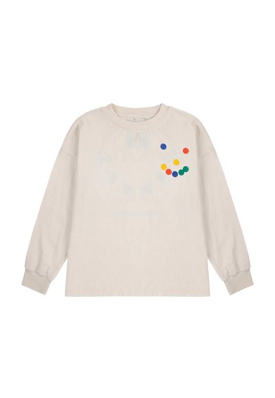Kremasta košulja dugih rukava s okruglim izrezom, koja na prsima ima šareni točkani uzorak u plavoj, žute, zelenoj i crvenoj boji.