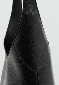 Sac en cuir noir avec une surface texturée, une forme effilée et des coutures lisses le long des bords. Poignées sur le dessus pour le transport.