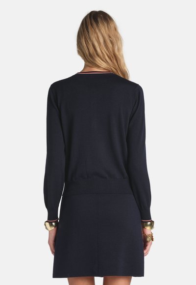 Marineblauer Strickpullover mit langen Ärmeln, tailliertem Rippenbund und einem Rundhalsausschnitt mit kontrastierenden Streifen. Glatte Textur.