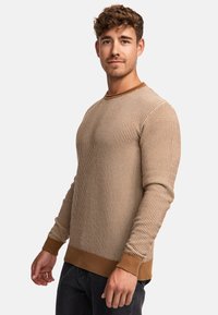 Beige, gerippter Strickpullover mit langen Ärmeln, rundem Halsausschnitt und kontrastierenden braunen Bündchen und Saum. Glatte Textur mit taillierter Form.