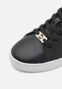 Schwarze Ledersneaker mit glatter Oberfläche, tonalem Nähen, runder Zehenpartie und weißer Gummisohle. Goldene Hardware verziert die Schnürsenkel.