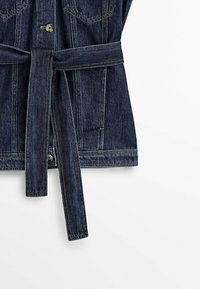 Veste en jean bleu foncé avec surpiqûres contrastantes, fermeture à boutons et une longue ceinture en tissu nouée à la taille, présentée sur fond blanc.