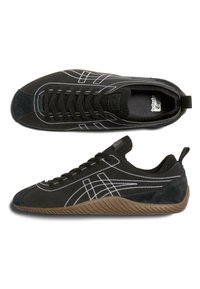 Černé semišové tenisky s bílým šitím, gumovou podrážkou a nízkým profilem. Mají hladký povrch a poutko na patě.