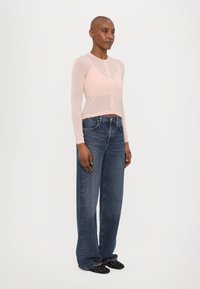 Lys rosa, langermet cardigan med knapplukking, kombinert med vide blå denimjeans. Glatt tekstur med en avslappet passform.