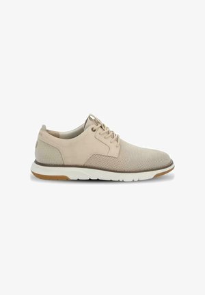 Zapatilla casual beige de perfil bajo con parte superior de malla, cierre de cordones, cuello acolchado, suela blanca y detalles marrones en la suela exterior y el ribete.