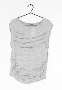 Šedý top s krátkým rukávem a zakulaceným výstřihem, který má texturovaný vzor malých bílých teček a šedých akcentů po celém povrchu.