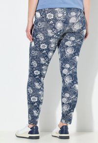 Leggings marinos con un patrón floral blanco en espiral, hechos de tela elástica. Presentan un diseño ajustado y una cintura de altura media.