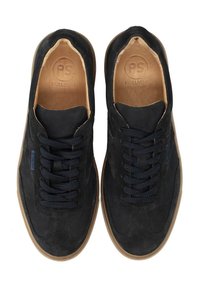 Zapatillas de ante negra con cordones azul marino, suelas de goma y plantillas de cuero. Presentan un logotipo en el costado y un diseño clásico de caña baja.