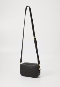 Sac bandoulière noir en simili cuir texturé, de forme rectangulaire, avec des accessoires en métal doré et une bandoulière ajustable.