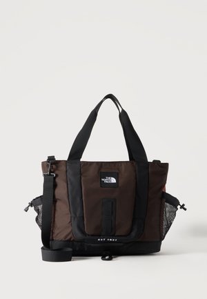 Borsa tote North Face marrone e nera con doppi manici, tracolla regolabile e tasche laterali in rete su sfondo semplice.