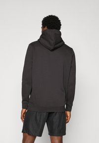 Zwarte hoodie met een trekkoordcapuchon, geribde manchetten en zoom. Draag met zwarte shorts, die een soepele textuur en casual ontwerp hebben.
