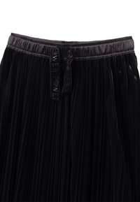 Gonna nera plissettata con elastico in vita, caratterizzata da due etichette in tessuto impresse con la scritta "POWER". Realizzata in un materiale leggero e testurizzato.