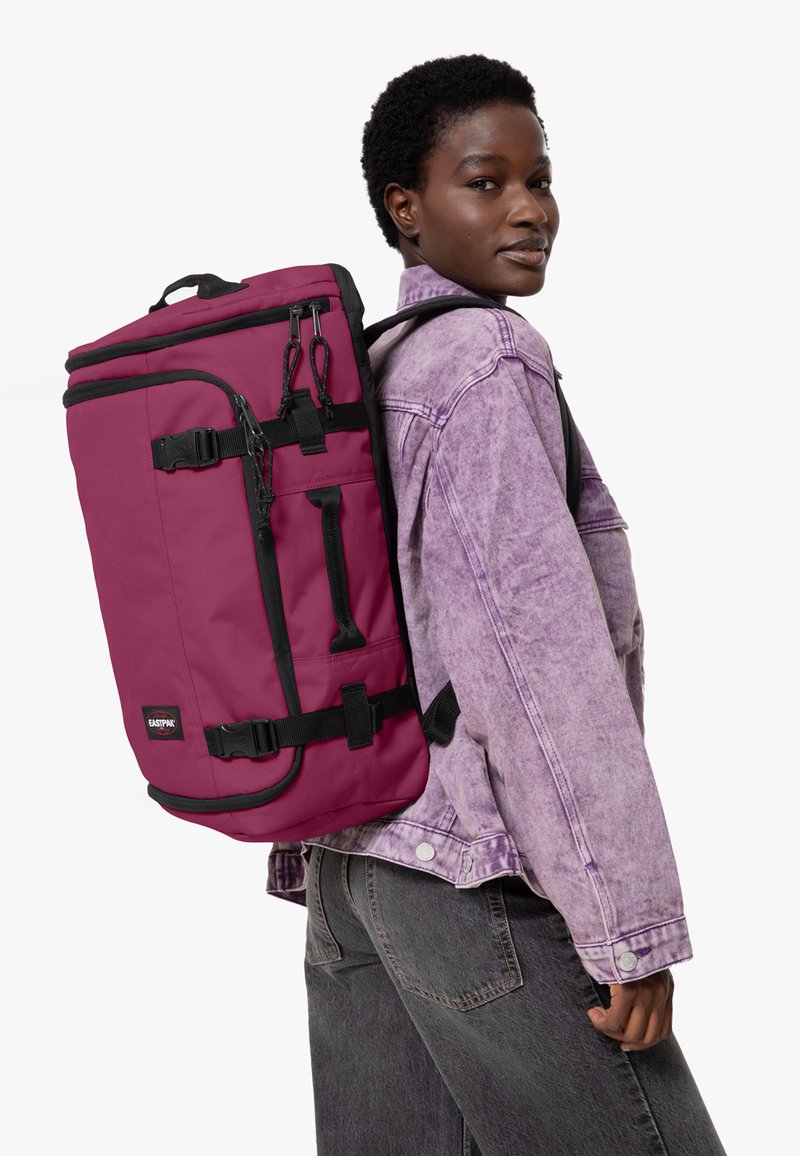 Bordová batoh s černými akcenty, s nastavitelnými popruhy, několika přihrádkami a kovovými detaily. Vyrobeno z odolného, texturovaného materiálu.