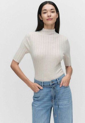Ljusbeige ribbad topp med korta ärmar och hög krage, kombinerad med ljusblå högmidjade jeans med dragsko och fickor.