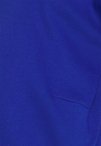 Tissu en coton bleu royal avec une texture lisse, doté d'un petit détail de poche. Le matériau semble léger et légèrement extensible.