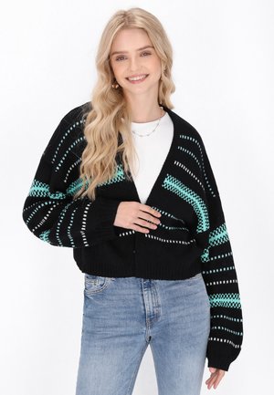 Černý pletený cardigan s tyrkysovými a bílými pruhy. Má výstřih do V, oversized rukávy a žebrované manžety.