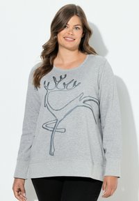 Sudadera gris de manga larga con escote redondeado, que presenta un diseño abstracto de reno en negro. Tela suave y corte relajado.