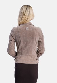 Suède jas in licht taupe met een fitted ontwerp, notch-kraag en dubbele gesp-accenten bij de taille. Gelaagde, gladde afwerking.
