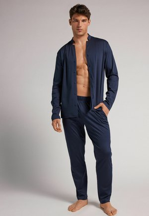 Ensemble de détente bleu marine comprenant un haut à manches longues avec boutons et un pantalon à taille élastique, fabriqué dans un tissu lisse et extensible.