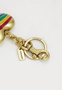 Gold-tone metal hardware with a colorful heart-shaped charm featuring red, green, and blue stripes; engraved "COACH" accents visible.