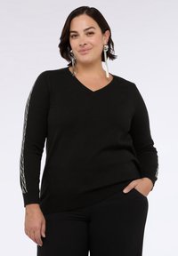 Czarny sweter z dzianiny z dekoltem w serek, dopasowany krój, długie rękawy z dekoracyjnymi srebrnymi elementami po bokach.