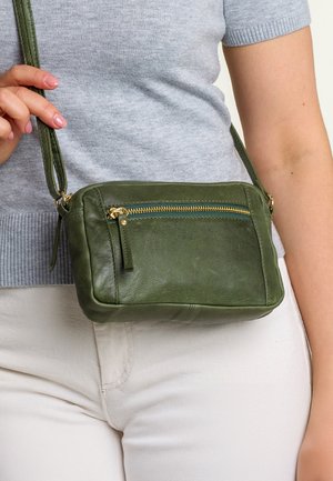 Borsa a tracolla verde in pelle con chiusura a zip dorata, dotata di una tasca frontale e di una tracolla removibile. Superficie textured con bordi arrotondati.
