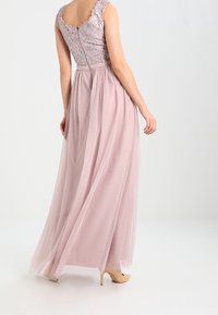 Lang, mouwloos, lila avondjurk met een kant bodice en tule rok. Heeft een aangesloten taille en een rits aan de achterkant.